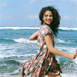 woman with brown hair wearing a deep v cut flowy dress with red ginger and tiare print 