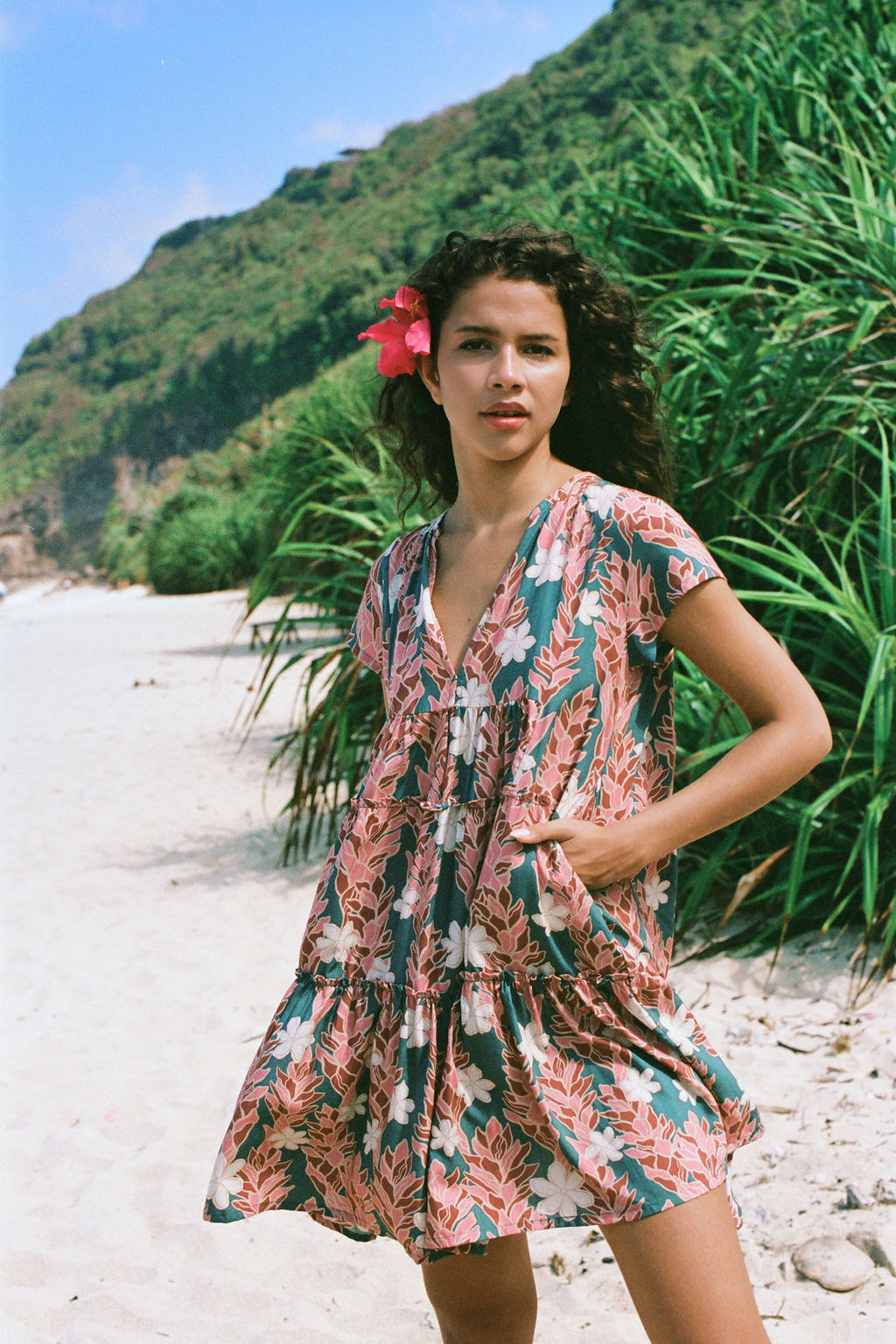 woman with brown hair wearing a deep v cut flowy dress with red ginger and tiare print 