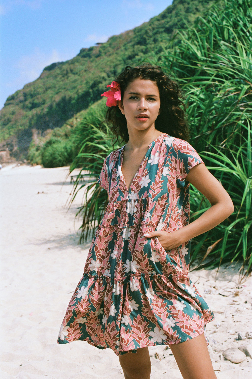 woman with brown hair wearing a deep v cut flowy dress with red ginger and tiare print 