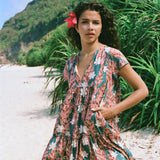 woman with brown hair wearing a deep v cut flowy dress with red ginger and tiare print 