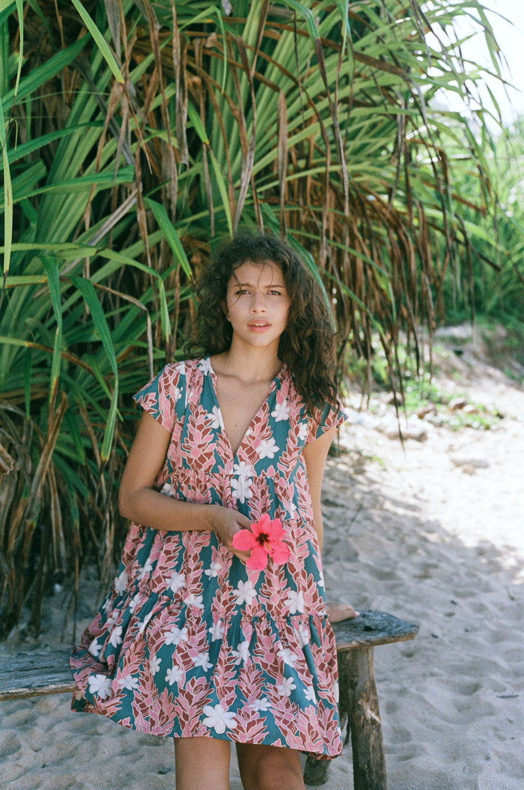 woman with brown hair wearing a deep v cut flowy dress with red ginger and tiare print 