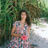woman with brown hair wearing a deep v cut flowy dress with red ginger and tiare print 