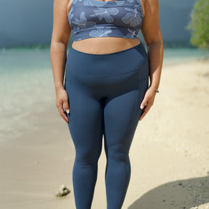 woman wearing a sports bra with blue hibiscus pattern and blue workout legging with pockets