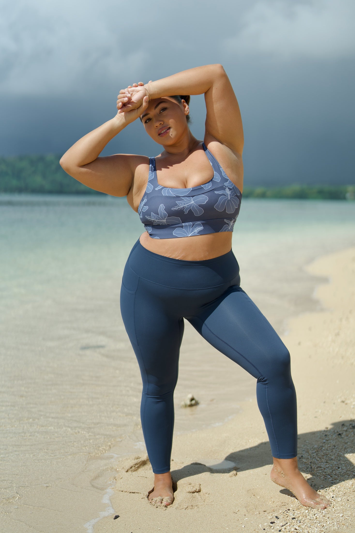 woman wearing a sports bra with blue hibiscus pattern and blue workout legging with pockets