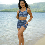 woman wearing a matching sports bra and pocket shorts workout set with blue hibiscus pattern