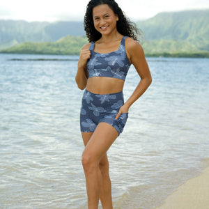 woman wearing a matching sports bra and pocket shorts workout set with blue hibiscus pattern