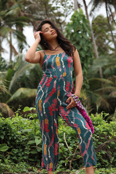 woman with brown hair wearing dark teal high neck jumpsuit with shell lei print