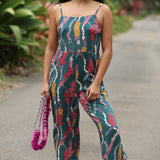 woman with brown hair wearing dark teal high neck jumpsuit with shell lei print