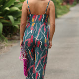 woman with brown hair wearing dark teal high neck jumpsuit with shell lei print