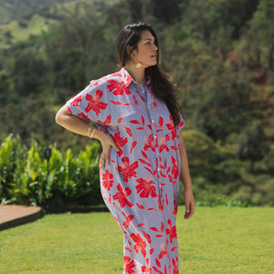 woman with brown hair wearing a maxi button up dress with periwinkle background and bright red hibiscus print.