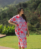 woman with brown hair wearing a maxi button up dress with periwinkle background and bright red hibiscus print.