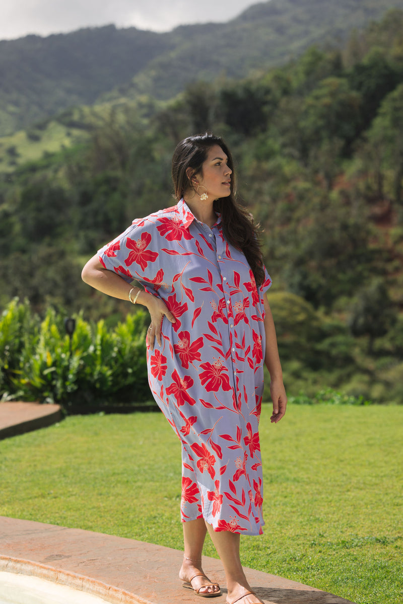 woman with brown hair wearing a maxi button up dress with periwinkle background and bright red hibiscus print.