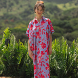 woman with brown hair wearing a maxi button up dress with periwinkle background and bright red hibiscus print.