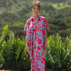 woman with brown hair wearing a maxi button up dress with periwinkle background and bright red hibiscus print.