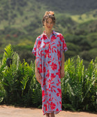 woman with brown hair wearing a maxi button up dress with periwinkle background and bright red hibiscus print.