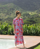 woman with brown hair wearing a maxi button up dress with periwinkle background and bright red hibiscus print.