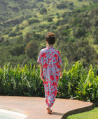 woman with brown hair wearing a maxi button up dress with periwinkle background and bright red hibiscus print.