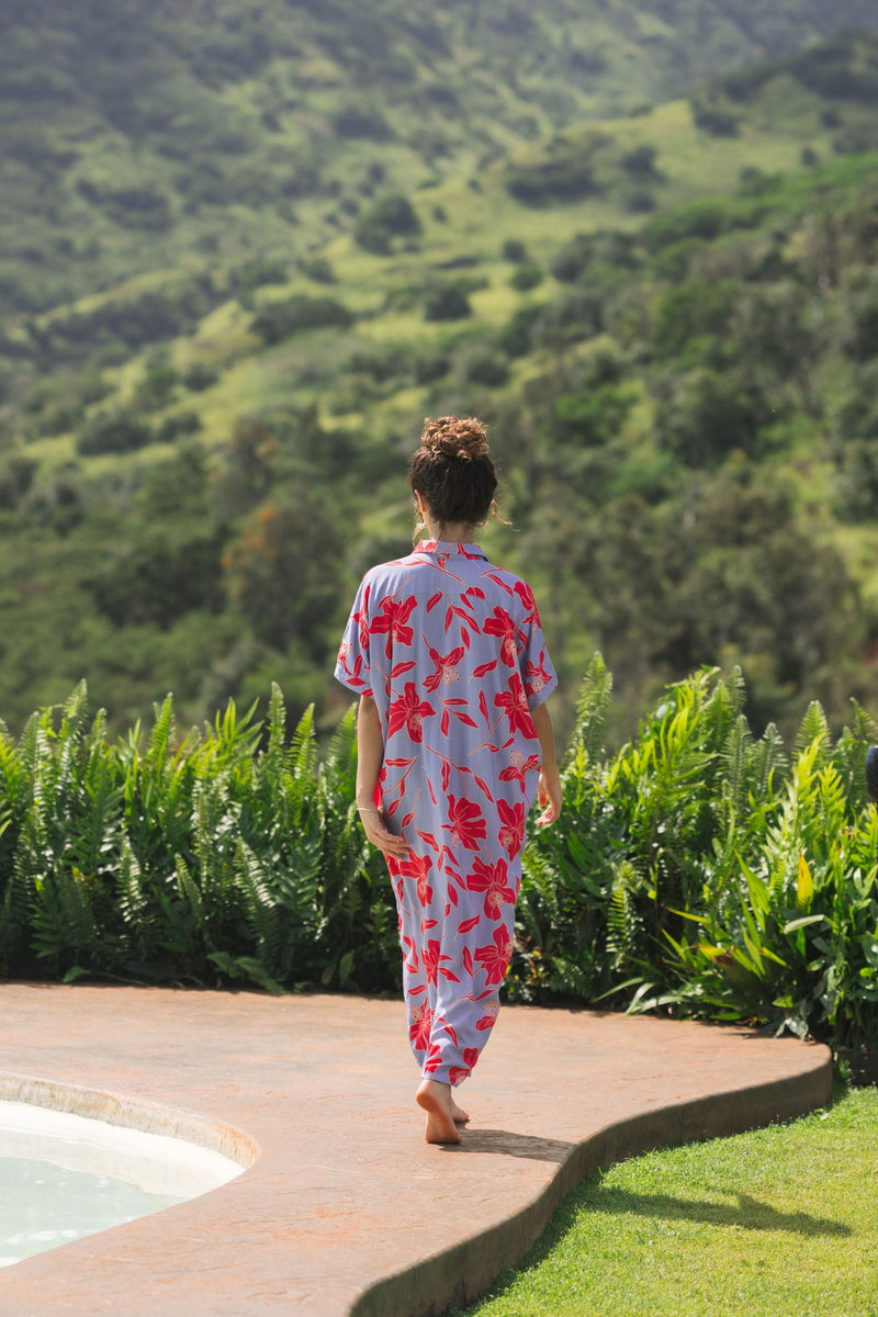 woman with brown hair wearing a maxi button up dress with periwinkle background and bright red hibiscus print.