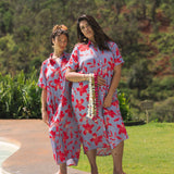 woman with brown hair wearing a maxi button up dress with periwinkle background and bright red hibiscus print.
