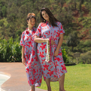 woman with brown hair wearing a maxi button up dress with periwinkle background and bright red hibiscus print.