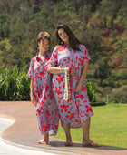 woman with brown hair wearing a maxi button up dress with periwinkle background and bright red hibiscus print.