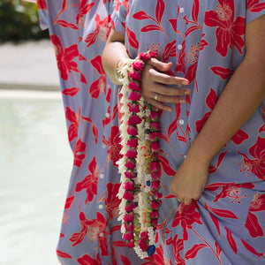 woman with brown hair wearing a maxi button up dress with periwinkle background and bright red hibiscus print.