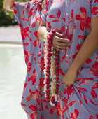 woman with brown hair wearing a maxi button up dress with periwinkle background and bright red hibiscus print.