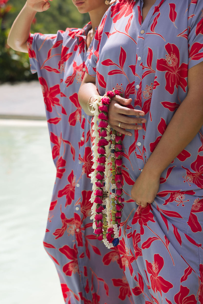 woman with brown hair wearing a maxi button up dress with periwinkle background and bright red hibiscus print.