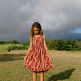 little girl wearing a red-brown tie back dress with ruffle hem and lei print