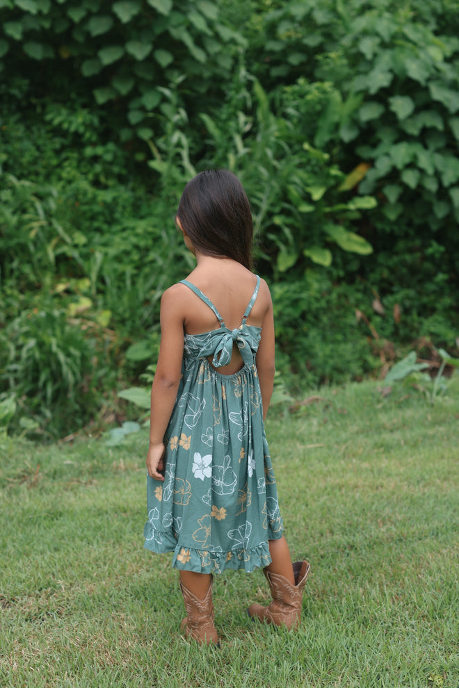 little girl wearing lush green tie back dress with puakenikeni print