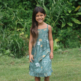 little girl wearing lush green tie back dress with puakenikeni print