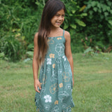 little girl wearing lush green tie back dress with puakenikeni print