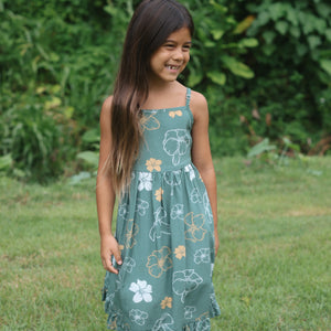 little girl wearing lush green tie back dress with puakenikeni print