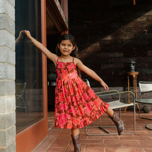 little girl wearing tie back dress with retro pink pua pattern