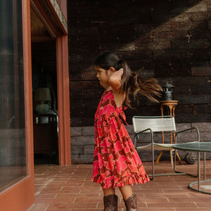 little girl wearing tie back dress with retro pink pua pattern