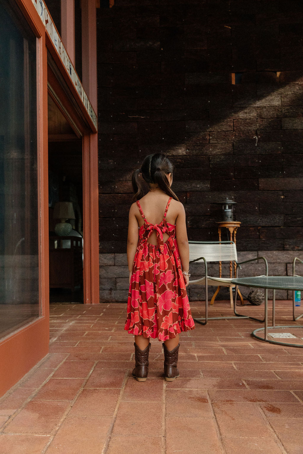 little girl wearing tie back dress with retro pink pua pattern