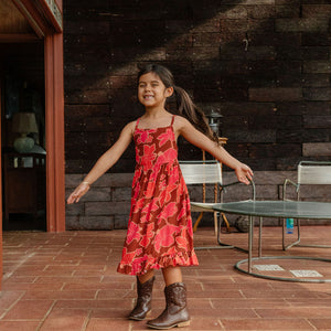little girl wearing tie back dress with retro pink pua pattern