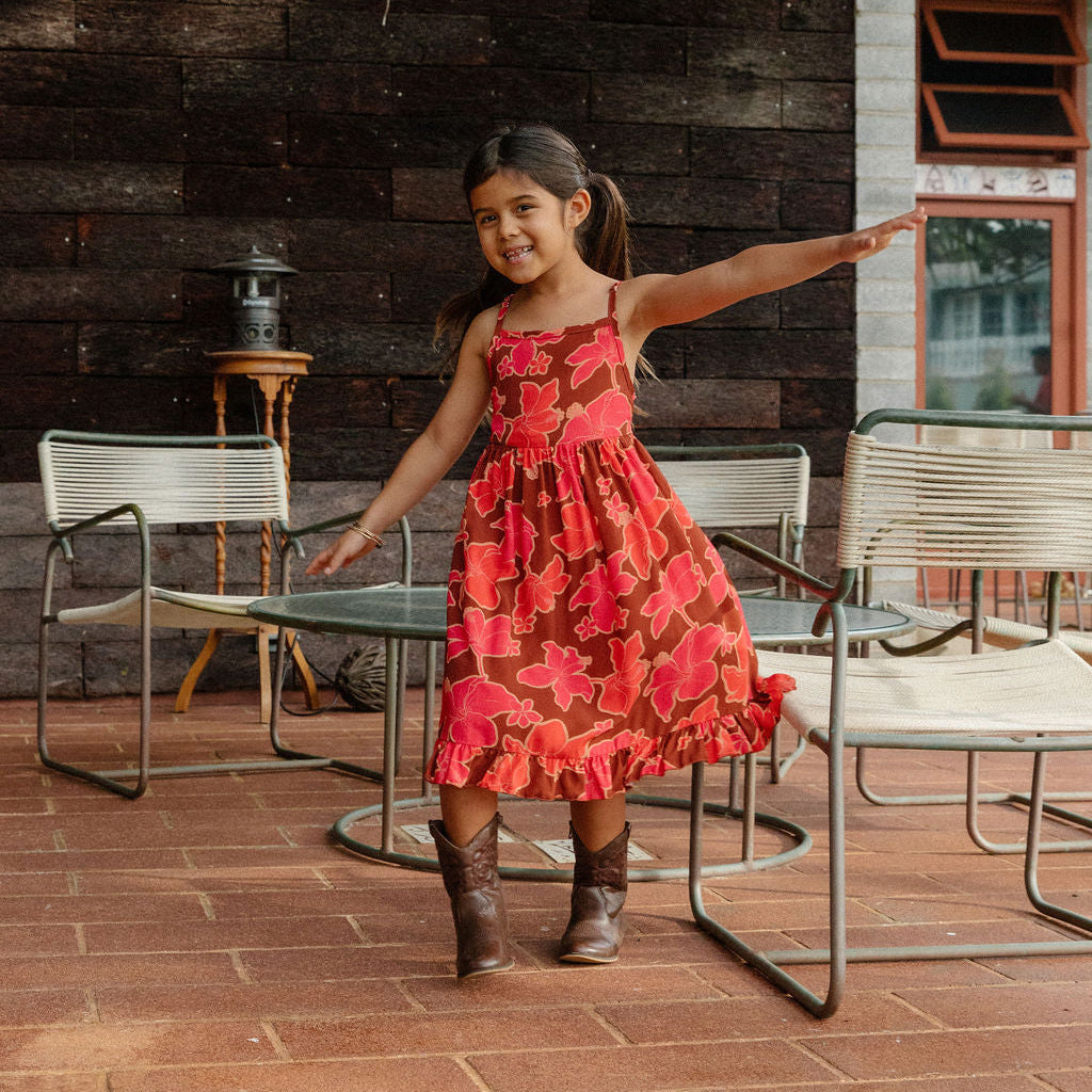 little girl wearing tie back dress with retro pink pua pattern