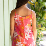 woman with brown hair wearing a bright pink spaghetti strap romper with retro flower print