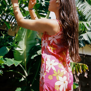 woman with brown hair wearing a bright pink spaghetti strap romper with retro flower print
