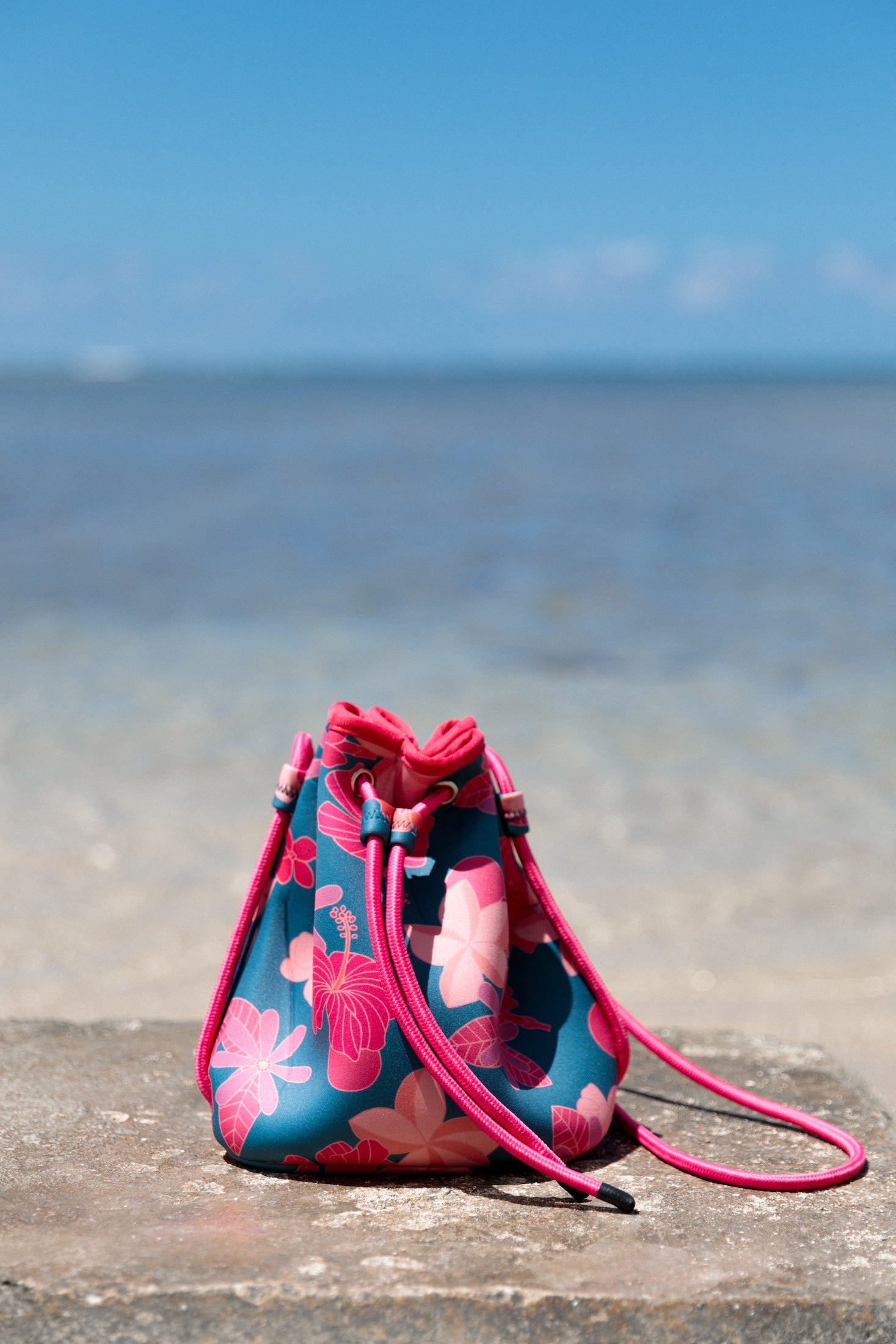 deep blue/teal neoprene drawstring crossbody purse with colorful floral pattern 