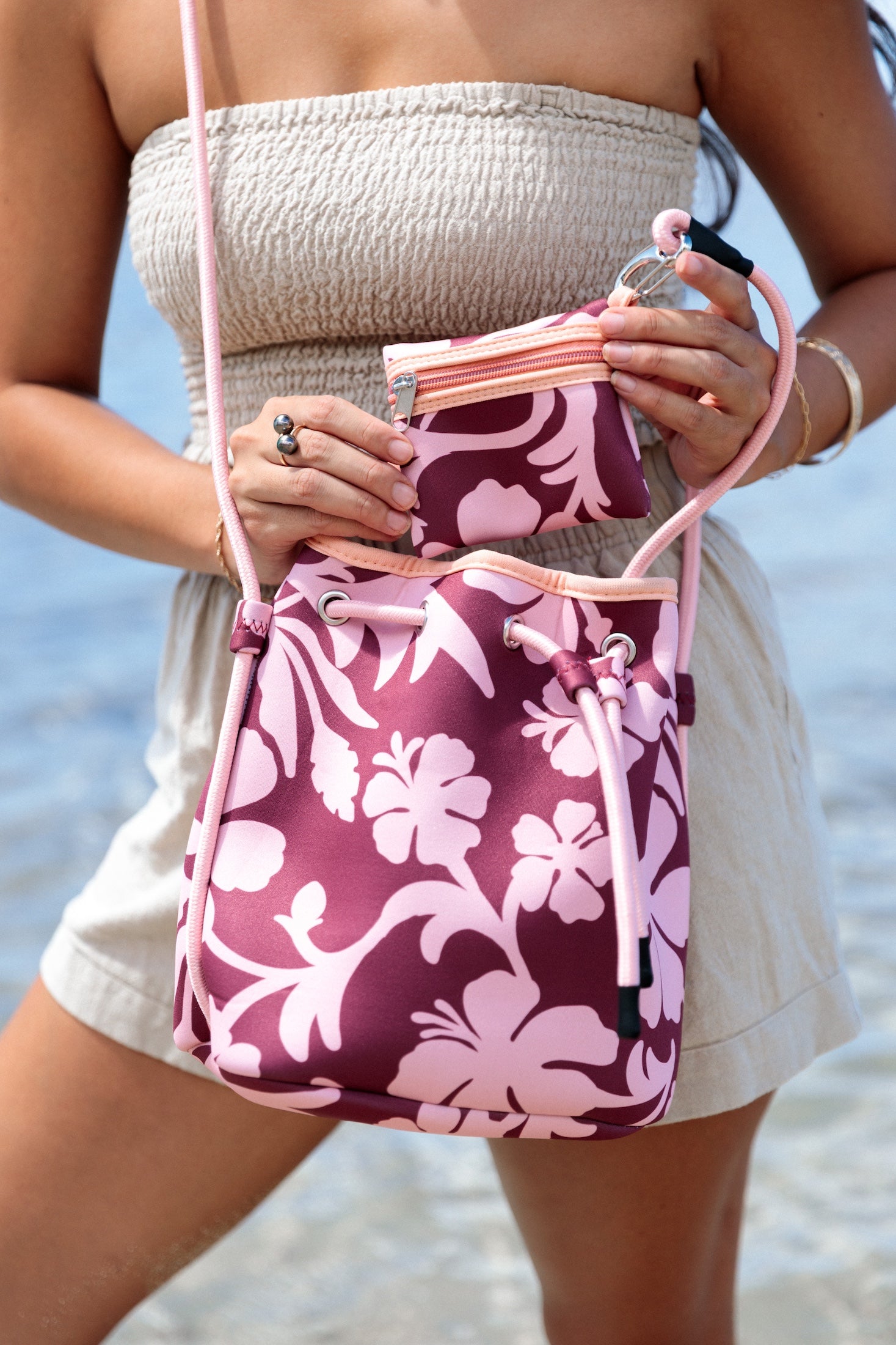 brown neoprene drawstring crossbody purse with pink hibiscus pattern