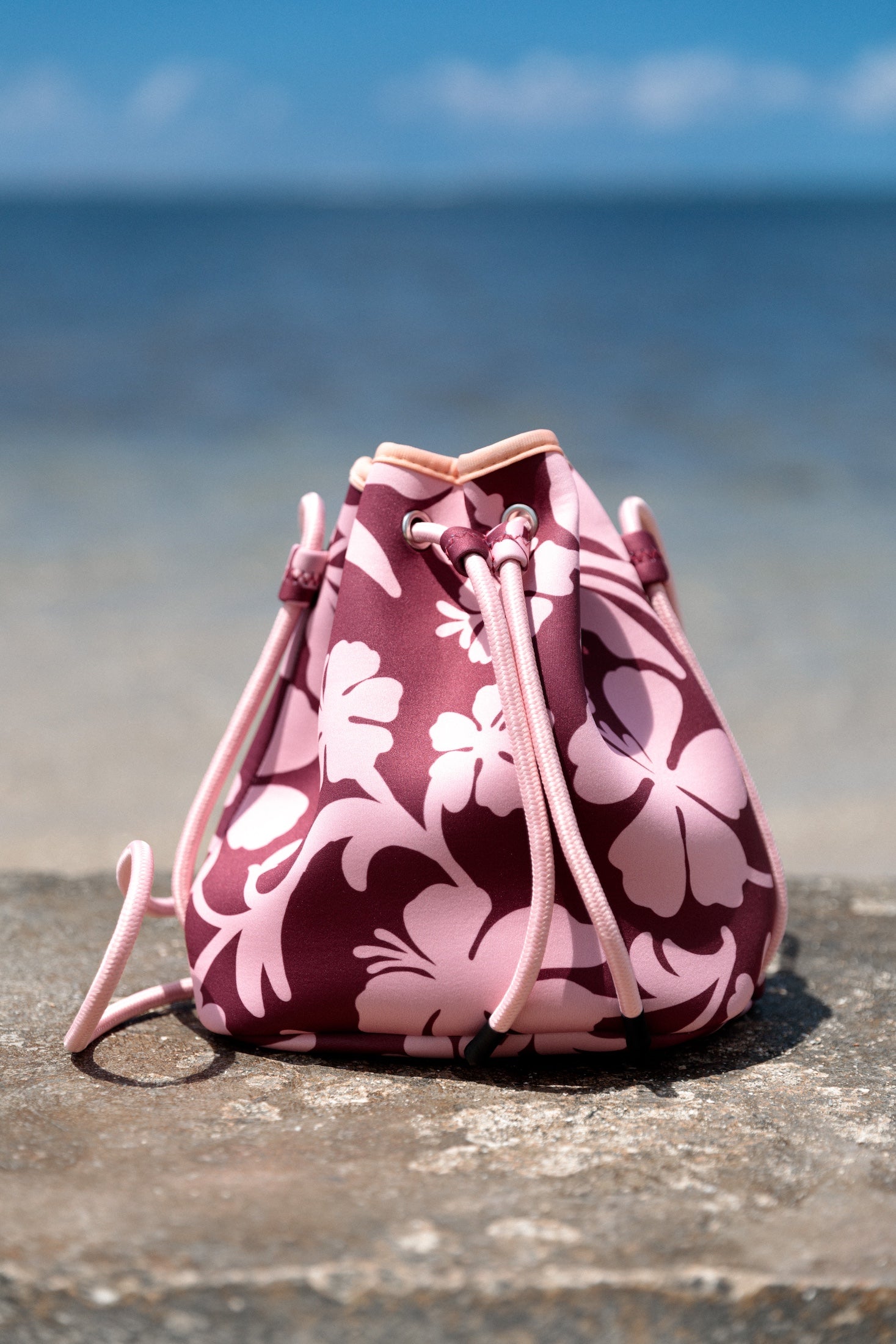 brown neoprene drawstring crossbody purse with pink hibiscus pattern