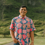man wearing a navy button up aloha shirt with bright pink hibiscus print