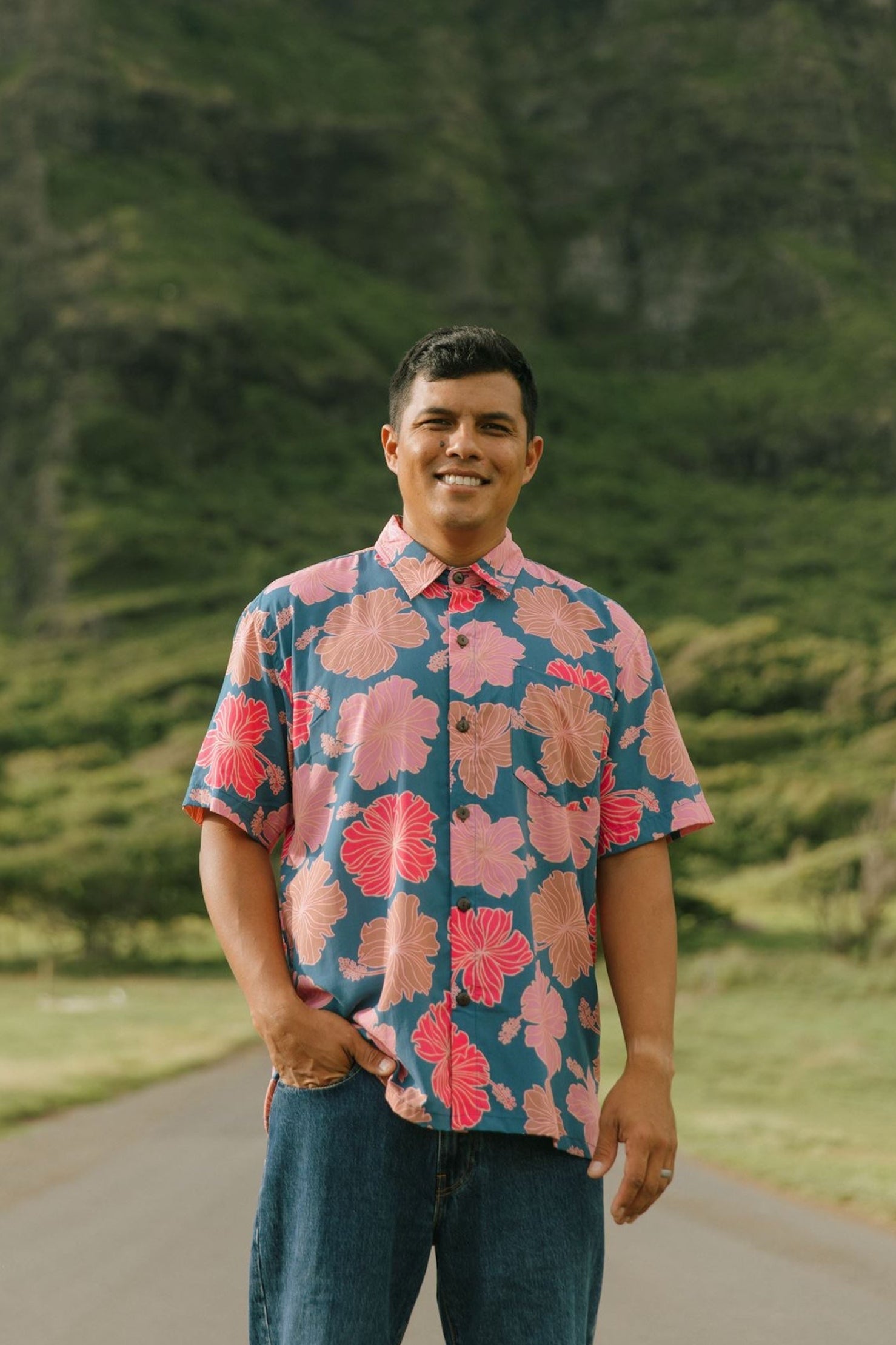 man wearing a navy button up aloha shirt with bright pink hibiscus print