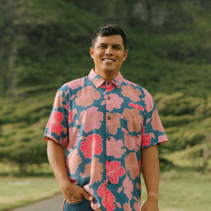 man wearing a navy button up aloha shirt with bright pink hibiscus print