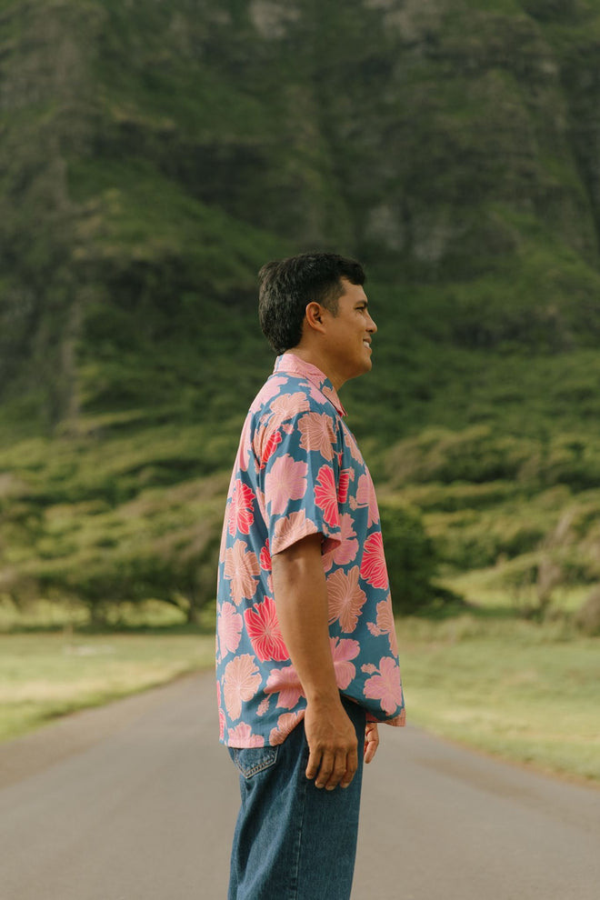 man wearing a nay button up aloha shirt with bright pink hibiscus print