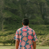 man wearing a nay button up aloha shirt with bright pink hibiscus print