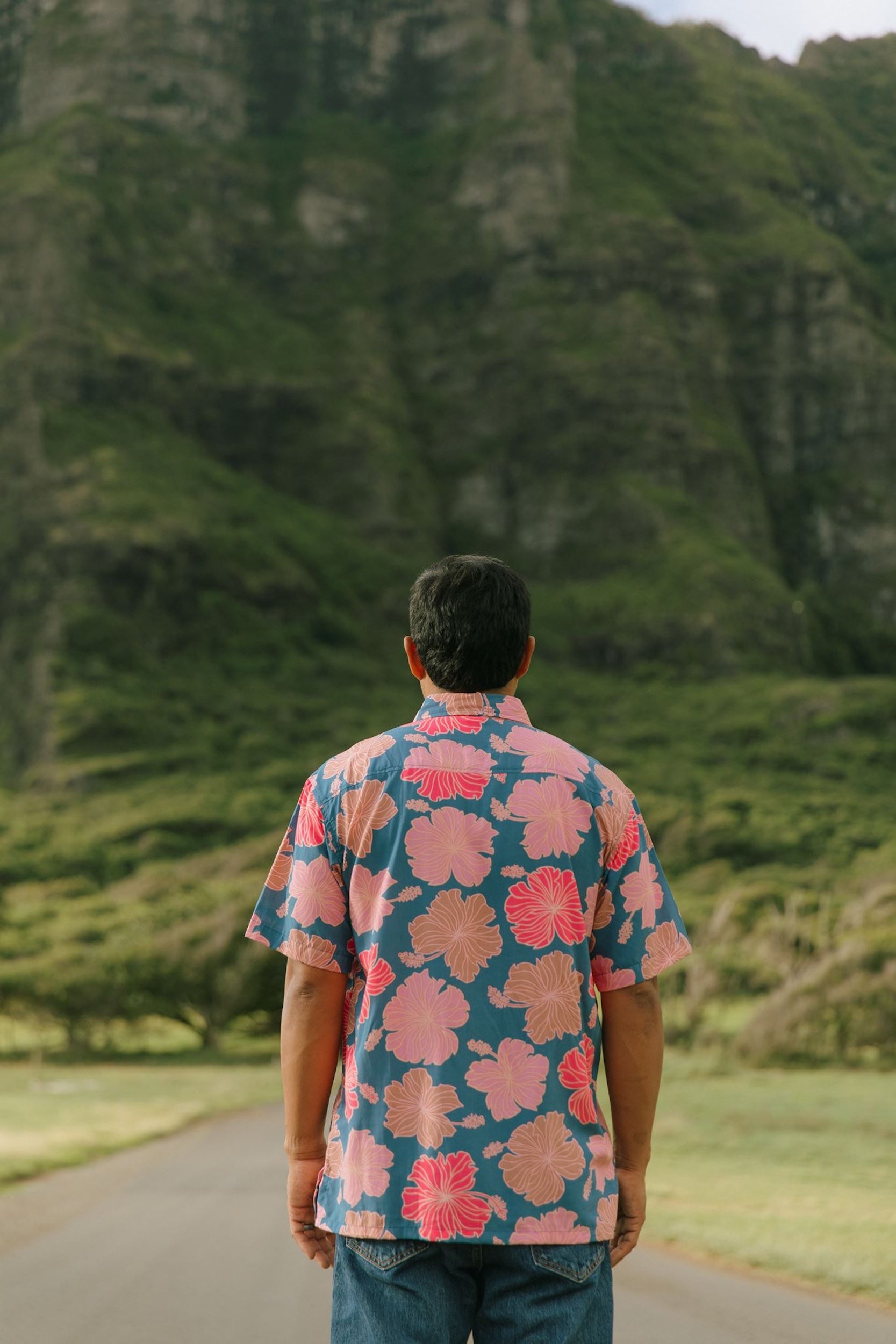 man wearing a nay button up aloha shirt with bright pink hibiscus print