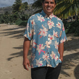 man wearing a teal aloha button up shirt with cream colored orchid pattern